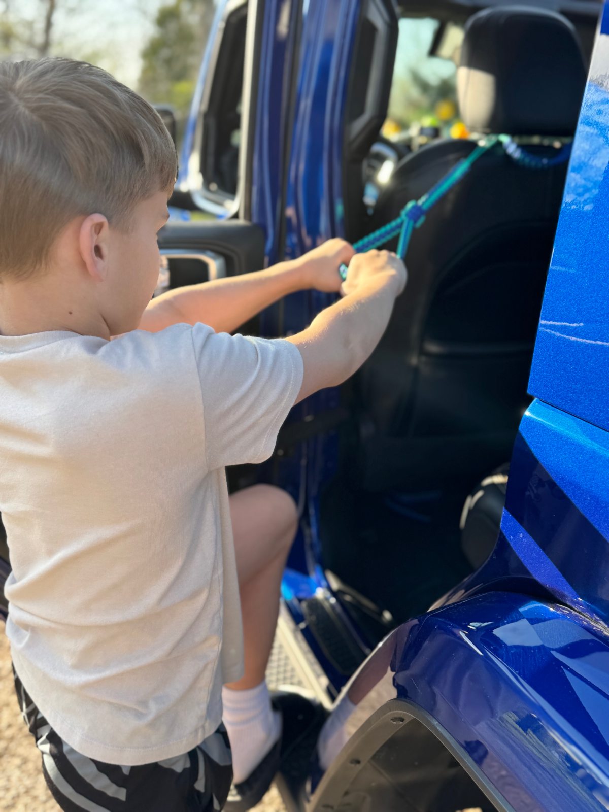 Child stepping into Jeep using paracord handle attached to headrest