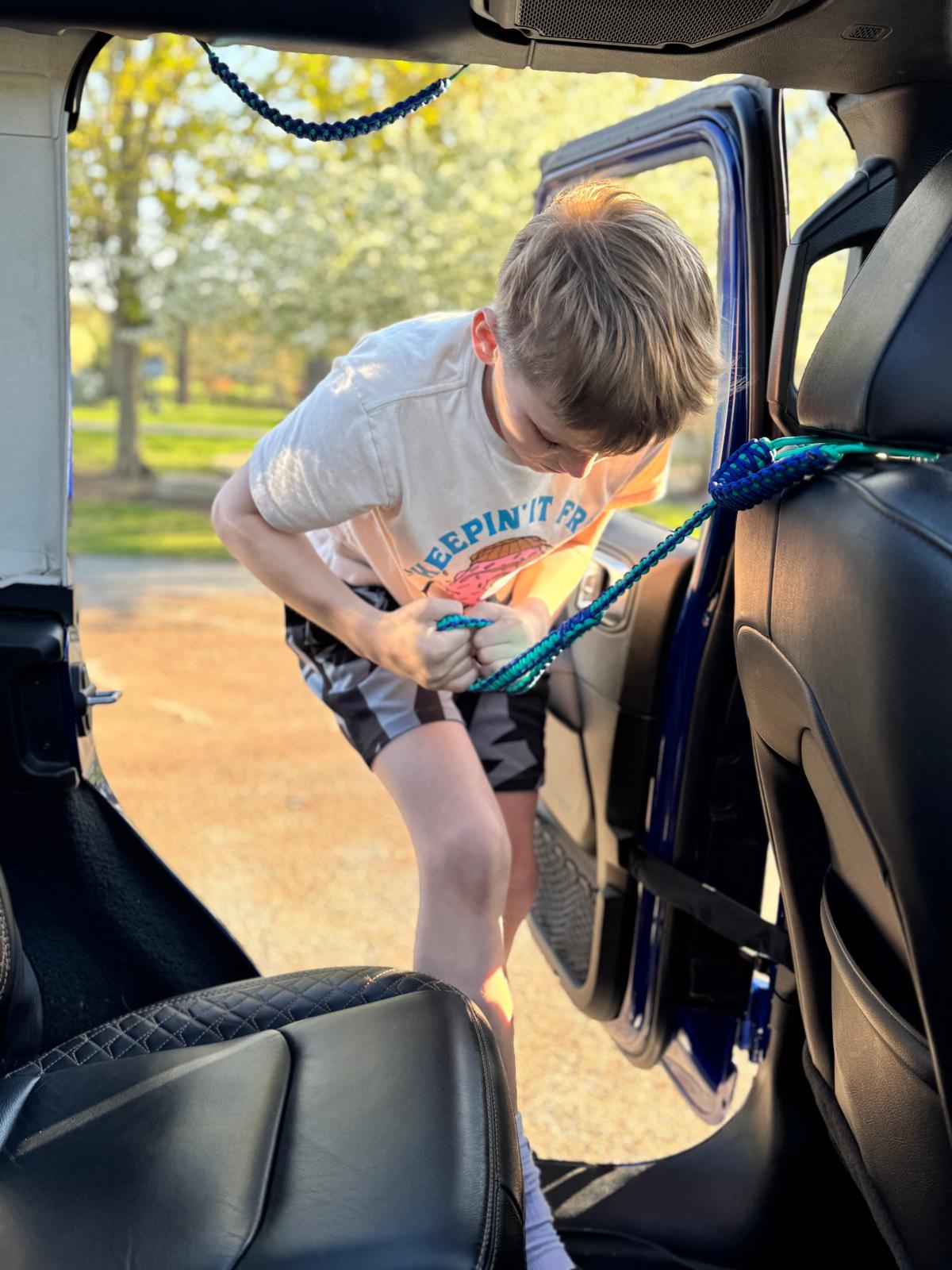 Child stepping into Jeep using paracord handle attached to headrest